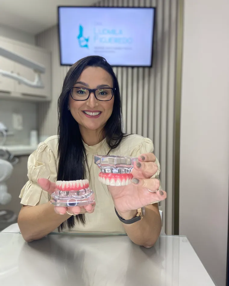 Dra. Ludmila Figueiredo apresentando modelo de prótese sobre implantes